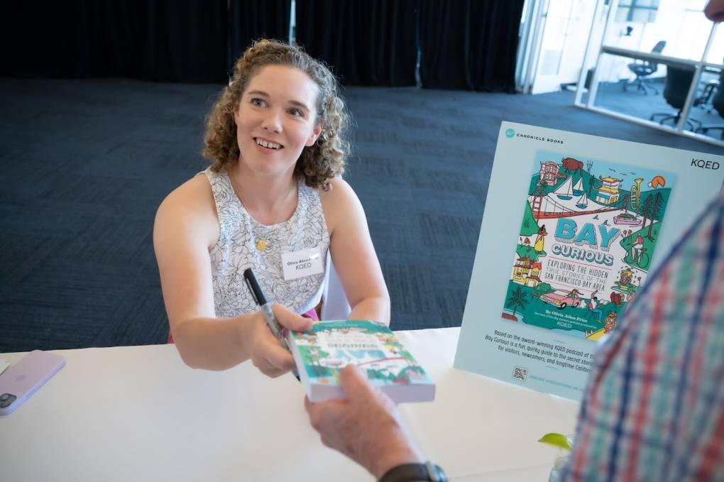 Bay Curious Host Olivia Allen-Price signs the book at a planned giving luncheon for KQED.